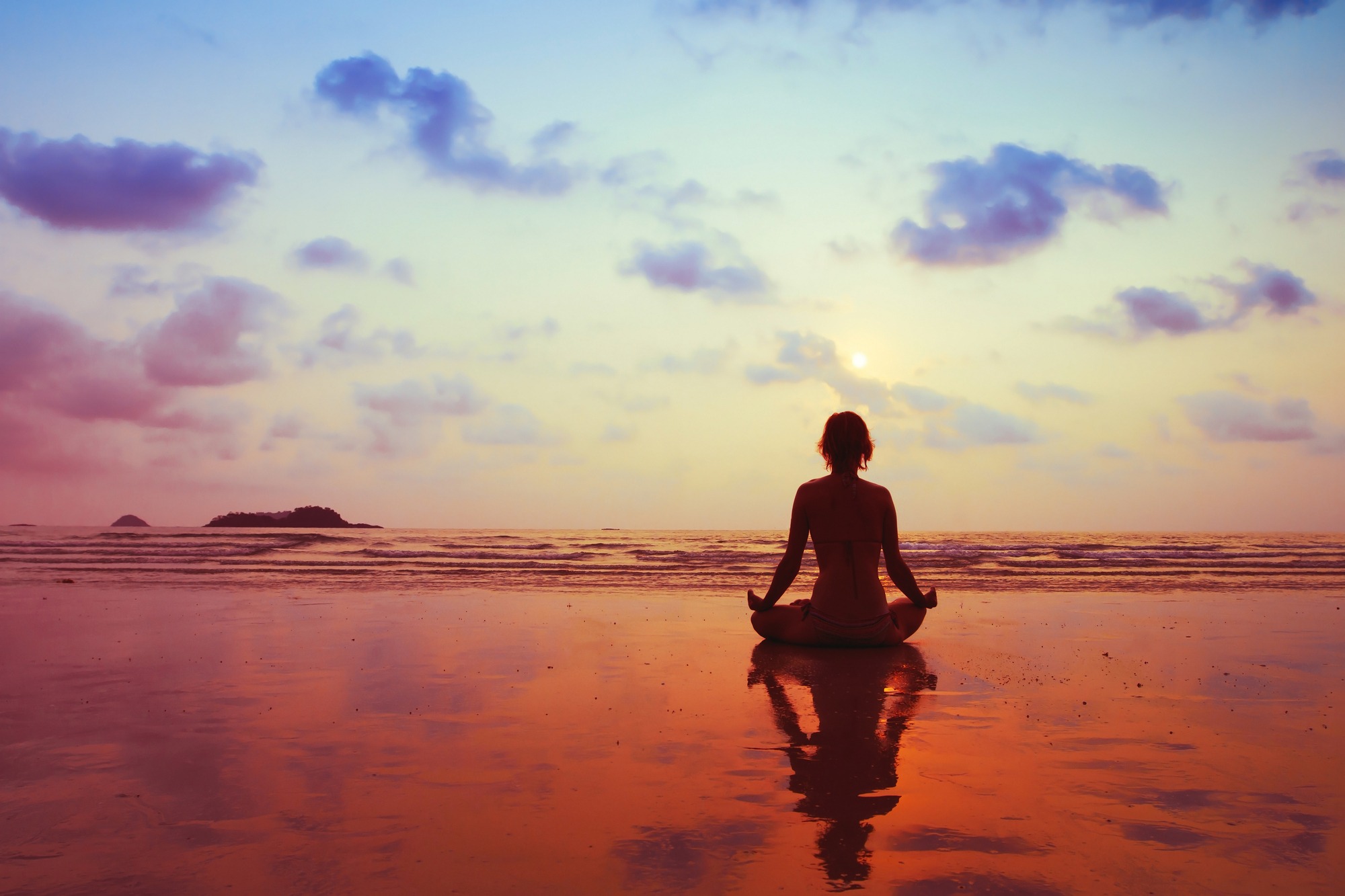 A woman meditates on the beach